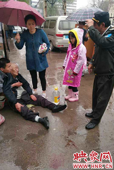 女孩為倒地老人撐傘。