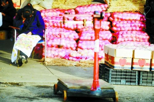 水果批發(fā)市場(chǎng)內(nèi)，沒(méi)有客戶時(shí)，商戶在繡十字繡