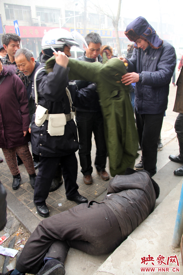一名熱心小伙將大衣脫下,蓋在倒地男子身上 一名熱心小伙將大衣脫下,蓋在倒地男子身上