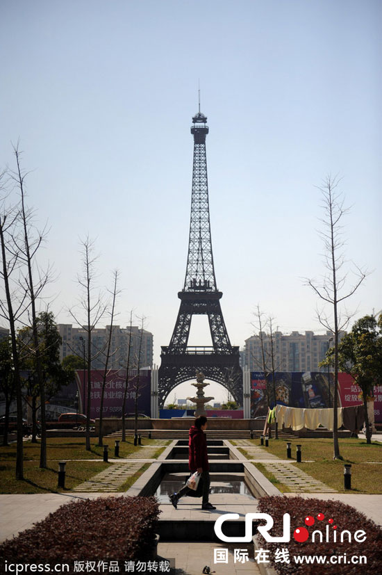 　2014年3月21日，杭州天都城，農(nóng)民在山寨埃菲爾鐵塔下耕作。圖片來源：東方IC