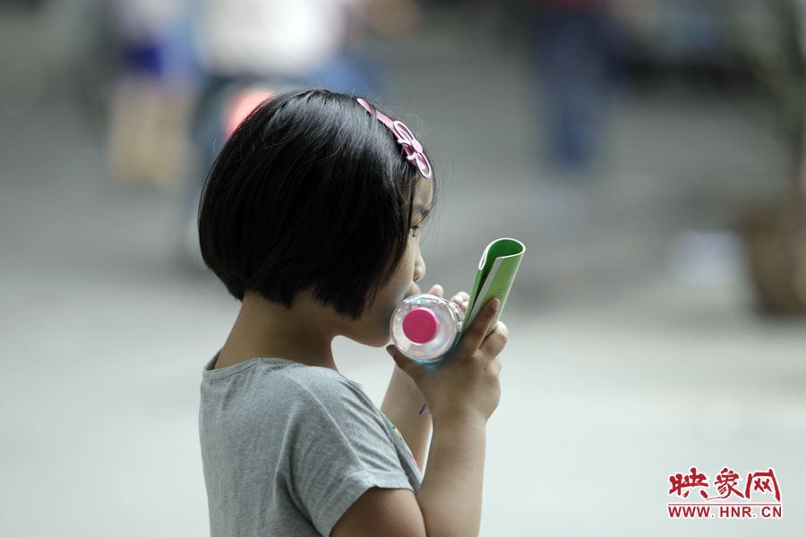 6月7日，鄭州回中考點(diǎn)，一名孩子拿著一瓶礦泉水，等待哥哥走出考場(chǎng)