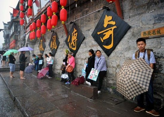 　4月29日上午11時(shí)20分，一些游客和古城當(dāng)?shù)氐木用穸阍谝粋€(gè)酒吧的屋檐下避雨。這些當(dāng)?shù)鼐用褚詾橛慰团恼罩\生，一場(chǎng)降雨讓他們的生意更加清淡。