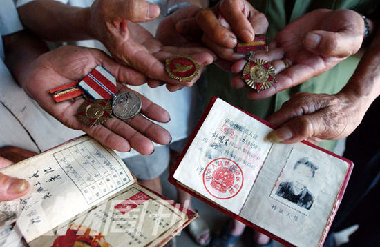 幾位志愿軍老兵展示自己的立功證、傷殘軍人證與勛章