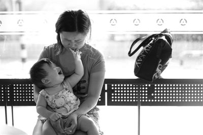 昨日，肯德基京廣中心店門口，姜女士提起跟養(yǎng)父母的關(guān)系時(shí)落淚，懷中9個月的女兒笑著跟她玩。新京報(bào)記者 薛珺 攝