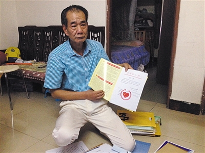 翻出一家網(wǎng)站贈(zèng)予的“中國(guó)好人”證書，區(qū)少坤單膝跪在地上，“你看，我是中國(guó)好人啊?！?范春旭 攝