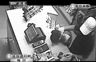 戴帽男子一手掐住加油站營業(yè)員，一手持發(fā)令槍指向另一營業(yè)員，要求“把錢給我裝起來”。