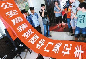 面對警方收繳的條幅，老板楊某也不好意思地用手遮擋臉