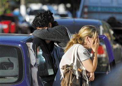 27日，遇難者親友在火災現(xiàn)場旁哭泣。