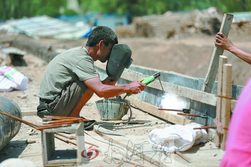 　正午陽(yáng)光下，工地上的焊接工人還在認(rèn)真工作。