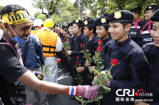 2013年12月03日,曼谷總理府與曼谷警署允許反政府示威民眾進(jìn)入,雙方進(jìn)入暫時(shí)“停戰(zhàn)”狀態(tài)迎接泰王生日。曼谷警察總署,女警們手持鮮花送給反政府示威民眾。圖片來源:Manish Swarup/東方IC