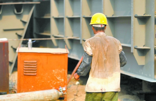 工地上，一建筑工人的衣服被汗水浸透。