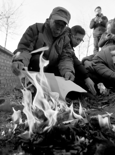 李三仁在兒子墳前焚燒再審無罪判決文書的復(fù)印件。新華社發(fā)