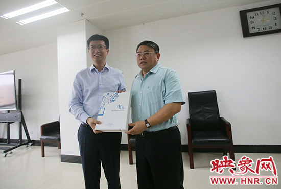 阿里云計算總裁胡曉明向河南省新聞出版廣電局局長朱夏炎遞交《中原云平臺交付手冊》。