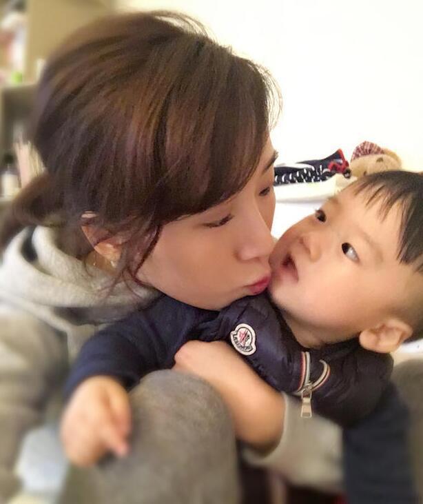 照片中李念狂吻兒子，小寶貝自顧自地玩著。