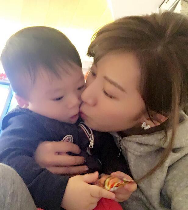 照片中李念狂吻兒子，小寶貝自顧自地玩著。