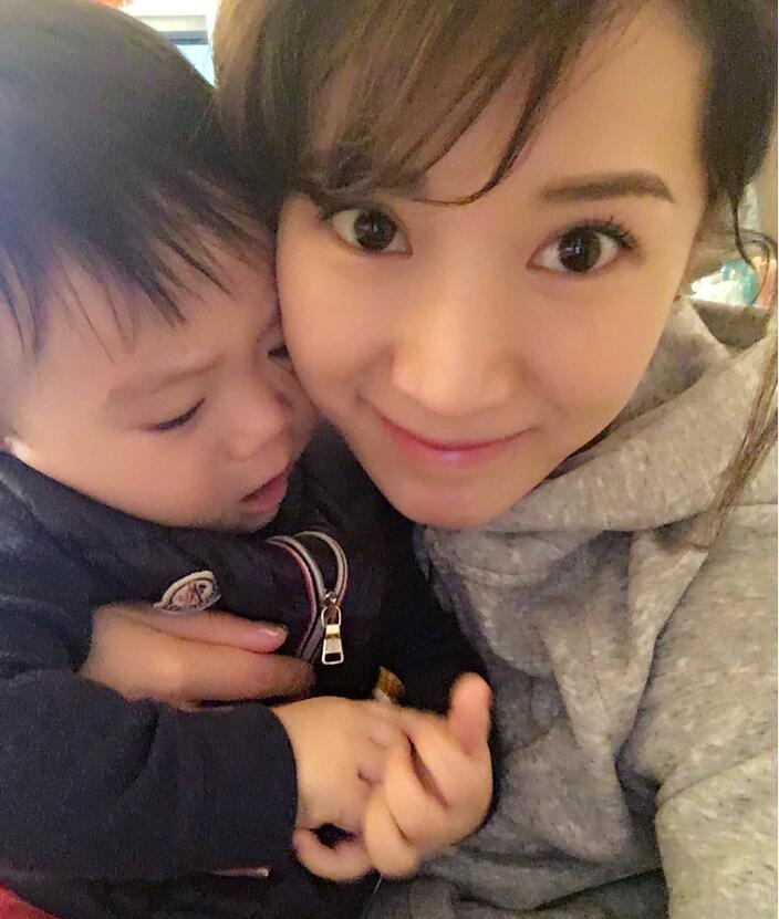 照片中李念狂吻兒子，小寶貝自顧自地玩著。