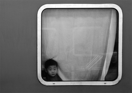 一個(gè)孩子把頭伸向窗外，他想再看送別的親人一眼