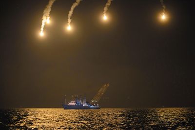 22日，搜救人員在照明彈的光亮下連夜搜救。