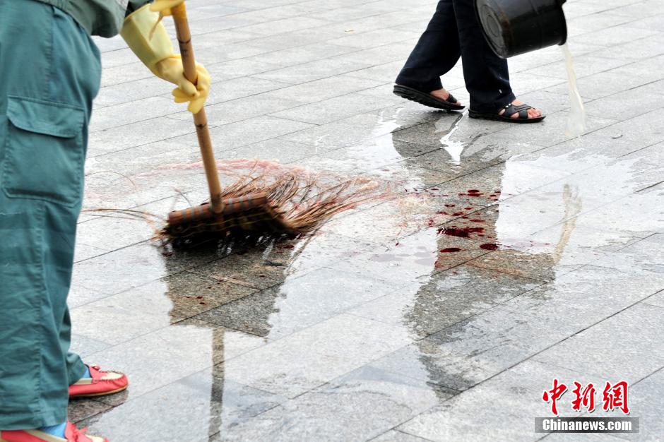 圖為環(huán)衛(wèi)工人在清理案發(fā)地點的血跡。