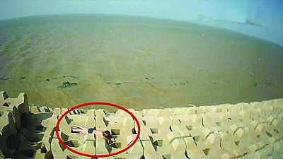 孫正龍游上岸，趴在海邊精疲力盡。