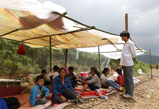 暴雨馬上來臨，村民們在簡易帳篷下躲雨。澎湃新聞 程藝輝 圖