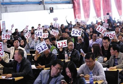 競(jìng)拍者正在練習(xí)舉牌動(dòng)作，以便拍賣時(shí)讓工作人員看清號(hào)牌。