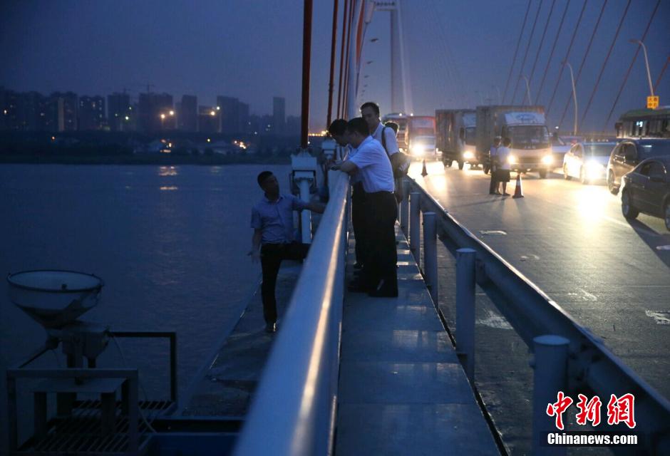 圖為武漢警方談判專家正在與翻爬至大橋外側(cè)護(hù)欄的劫持者談判。