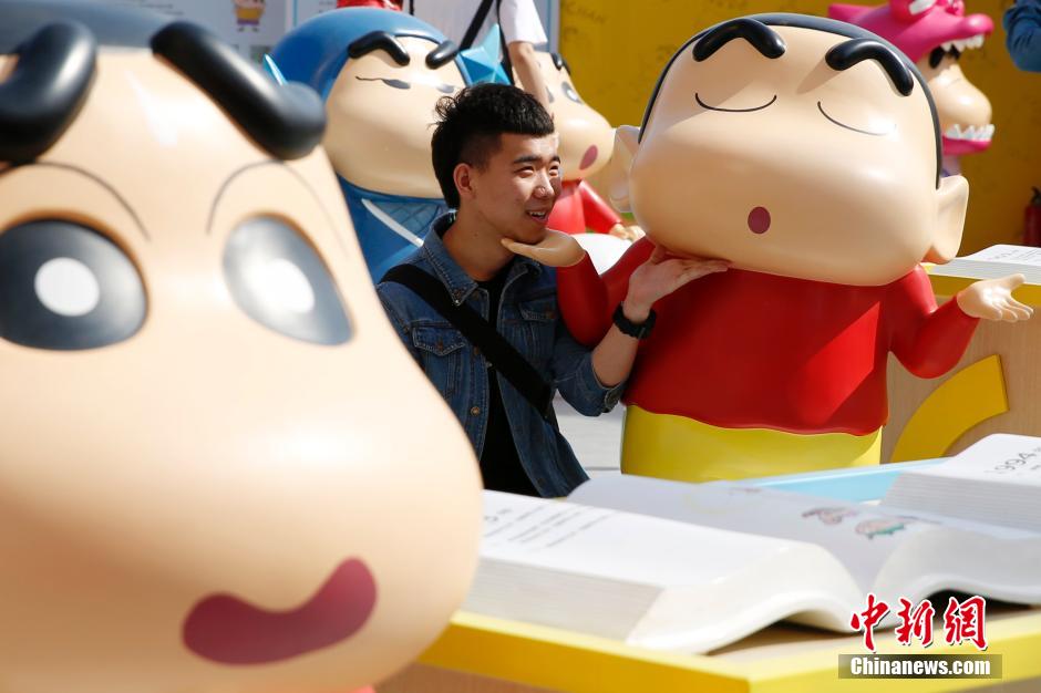 4月22日，游客與蠟筆小新合影?！跋灩P小新25周年紀(jì)念特展”日前在北京開(kāi)展，吸引了不少市民游客。