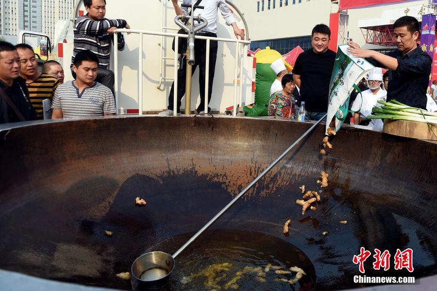 工作人員向大鍋內加入油和姜等烹飪調料。 圖片來源：CFP視覺中國