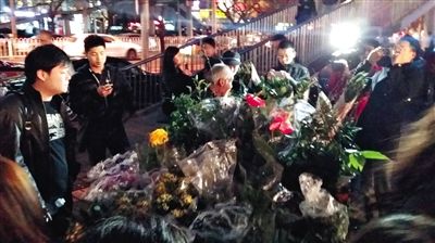 昨晚7時許，三里屯太古里西邊附近一過街天橋旁邊，聞訊而至的網(wǎng)友圍住了賣花老人，爭相買花。 網(wǎng)友“行者橙子”供圖